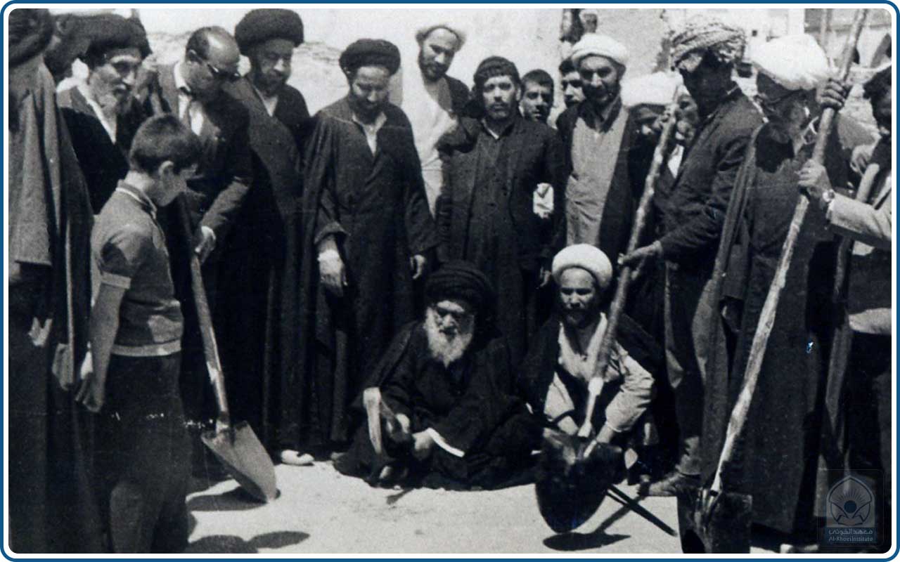 الإمام الخوئي (قدس سره) يحفر الأرض بالمعول وبجانبه أحد الحاضرين